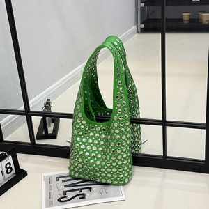 Green leather underarm bag with silver metal rivets shown on a modern mirrored display