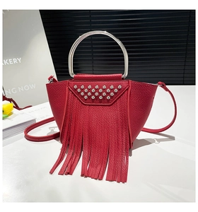 Dettaglio borsa in pelle rossa con borchie argento e lunghe nappe decorative