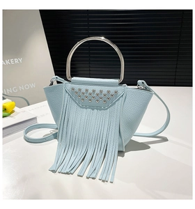 Dettaglio borsa a secchiello celeste con borchie argentate, frange in pelle e manico ad anello