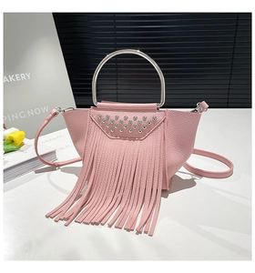 Dettaglio borsa rosa in pelle litchi con borchie argentate, frange lunghe e manico tondo