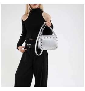 Dettaglio borsa quadrata argento con borchie indossata da modella in abito nero
