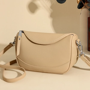 Minimalist beige pebble leather crossbody bag with adjustable strap and silver hardware