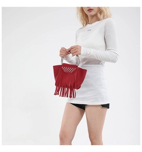 Dettaglio borsa rossa in pelle con borchie argentate, lunghe nappe e manico in metallo