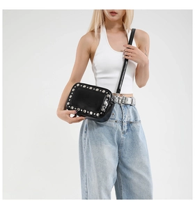 Detail van zwarte crossbodytas met zilveren klinknagels en glanzende lederen textuur