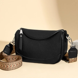 Detail of black pebbled leather shoulder bag with colorful woven bohemian strap