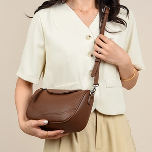 Detail of brown hobo bag with pebble leather texture and U-shaped stitching on model