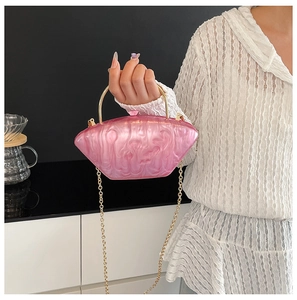 Dettaglio borsa da sera in acrilico rosa marmorizzato con manico in metallo oro