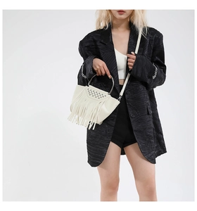 Dettaglio della borsa in pelle bianca con borchie argentate e lunghe nappe a frange
