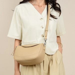 Detail of minimalist cream leather crossbody bag with lychee texture and silver hardware