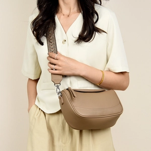 Detail of tan pebble leather crossbody bag with patterned wide woven shoulder strap