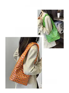Detail view of vibrant green and orange leather bucket bags with silver metal rivets