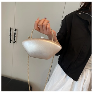 Dettaglio della pochette in acrilico bianco perla con manico dorato e tracolla a catena