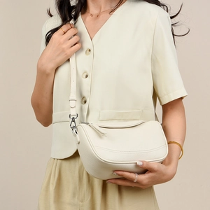 Detailed shot of beige lychee pattern faux leather texture on minimalist shoulder bag