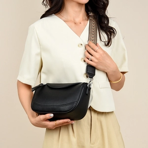 Detail of black lychee grain leather bag with stylish patterned woven strap on model