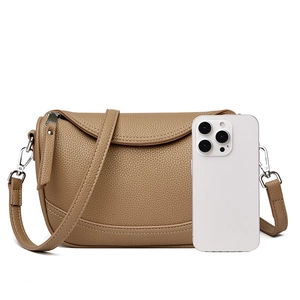 Detailed view of the tan pebble leather shoulder bag with a smartphone for size reference