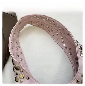 Close-up of pink leather handbag strap featuring silver metal rivets and fine stitching