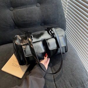 Glossy black vintage hobo bag with front pockets on a textured grey surface