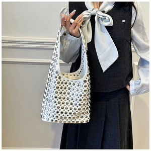 Close-up of white leather hobo bag with vintage metal rivets on model with minimalist wall