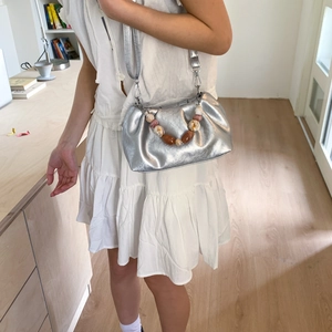 Silver metallic pleated cloud bag with unique oversized bead handle and shoulder strap