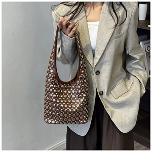Detail of silver rivets on dark brown leather shoulder bag with a half-moon hobo design