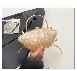 Dettaglio della borsa a mano in acrilico perlato con manico ad anello dorato e catena