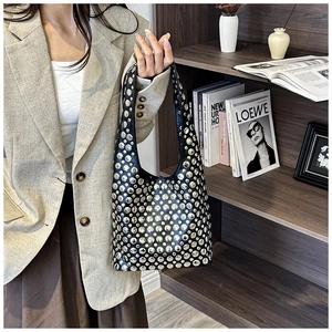 Detail of silver rivets on black leather hobo bag worn with a beige blazer