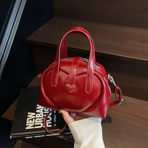 Chic red heart-shaped PU leather handbag with adjustable strap on wooden stairs