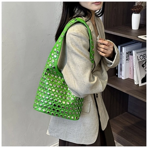 Close-up of bright green shoulder bag featuring dense silver stud rivets and a sleek handle