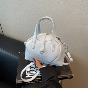 Light blue faux leather handbag with top handles and adjustable strap on a book