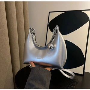 Close-up of metallic silver crescent bag with CLEAR heart logo and silver ball charm