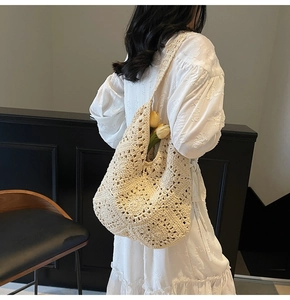 Detail der handgewebten cremefarbenen Hobo-Tasche mit floralem Lochmuster am Model