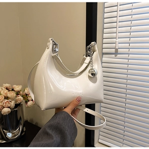 Detail of white patent leather crescent bag with silver ball charm and CLEAROK embossing
