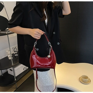 Detail of red patent leather dumpling bag with silver metal ball charm on a model