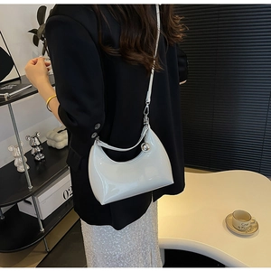 Detailed macro view of white patent leather shoulder bag with a silver sphere charm
