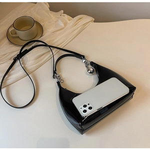 Close-up of black patent leather hobo bag with smartphone for size reference and scale