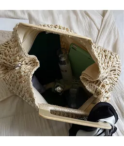 Detail view of woven straw tote bag with wood handles and spacious interior storage