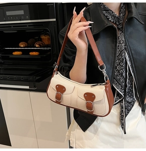 Detail der Canvas-Baguette-Tasche mit braunem Lederbesatz und Schnallen in Küchenkulisse