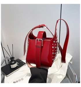 Détail du sac seau en cuir verni rouge avec rivets argentés et boucle métallique décorative