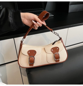 Detail der Canvas-Baguette-Tasche mit braunem Lederbesatz, Metallkette und Funktionstaschen