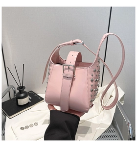Détail d'un sac seau rose avec clous argentés et boucle métallique en scène mode