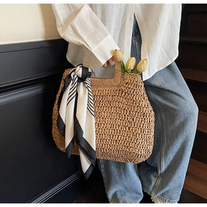 Detail of hand-woven straw tote with striped scarf and tulip on wooden stairs