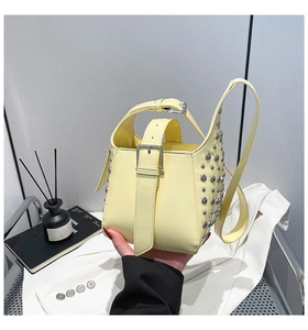 Détail du sac seau jaune vif avec clous argentés et bandoulière à boucle en gros plan