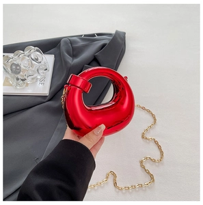 Dettaglio della borsa circolare rossa metallizzata con la sua sottile tracolla a catena dorata