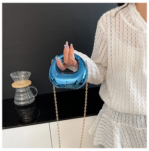 Detail of blue acrylic crescent handbag with mirror metallic finish and gold chain strap