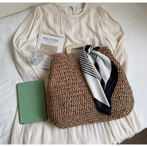 Detail of woven straw tote bag with wooden handles and a striped silk scarf accessory