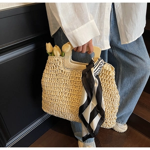 Detailed close-up of handmade straw tote with wooden handle and patterned silk scarf