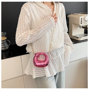 Mini borsa circolare rosa metallizzato con catena dorata su una modella