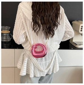 Mini borsa da sera rotonda rosa metallizzato con catena dorata indossata da modella