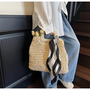 Detail showing the textured hand-woven straw tote with elegant square wooden handles