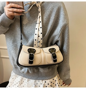 Detail der cremefarbenen Canvas-Tasche mit schwarzem Lederbesatz und zwei Metallschnallen